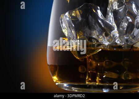 Alkoholischer Amber Whisky in einem Glas mit Eis auf schwarzem Hintergrund Stockfoto