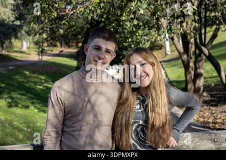 Ein junges Paar lächelt in die Kamera und begrüßt Glück und Freundschaft im Freien Stockfoto