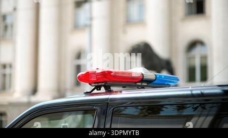 Polizeilichtbügel montiert an einem Streifenwagen mit roten und blauen Notlichtern in einer städtischen Umgebung. Stockfoto