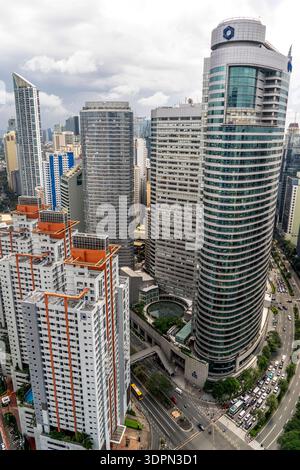 Blick aus der Vogelperspektive auf die moderne Skyline der Stadt mit hohen Bürotürmen und Apartmentgebäuden neben einer belebten, gekrümmten Straße unter bewölktem Himmel. Stockfoto