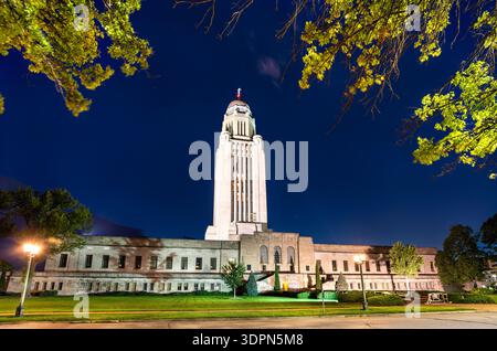 Nebraska State Capitol in Lincoln bei Nacht. Der historische Art déco-Wolkenkratzer verfügt über einen Kalksteinturm und eine goldene Kuppel, die vor einem dunkelblauen Himmel beleuchtet wird Stockfoto