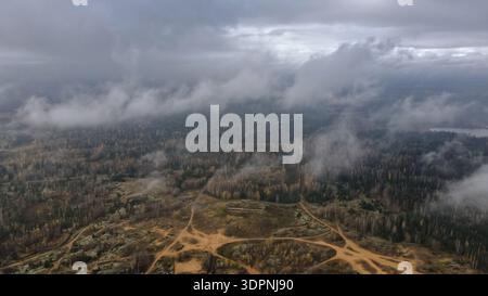 Die Luftaufnahme zeigt den Dretunski-Trainingsplatz in Weißrussland, gemischte Wälder, niedrige Wolken, Sandwege, freigelegte Pfade, und ein Bunkerhügel im Spätherbst Stockfoto