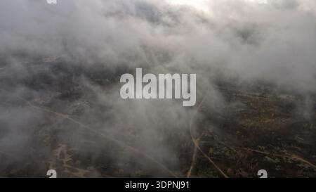 Die Drohnenansicht des Trainingsplatzes Dretunski in Belarus zeigt niedrige Wolken und Nebel über unbefestigten Wegen, schmutzige Wälder und eine sandige Straßenkreuzung Stockfoto