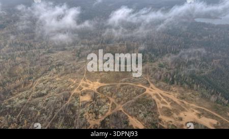 Die Drohnenansicht des Trainingsplatzes Dretunski in Weißrussland zeigt sandige Fahrzeugbahnen, eine Betonfeuerposition, aufgewühlte Erde, alte Krater, niedrige Clou Stockfoto