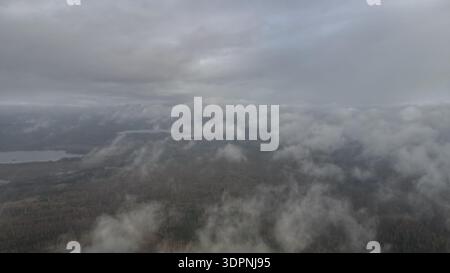 Die Drohnenansicht zeigt den Dretunski-Trainingsplatz in Weißrussland, Nebel über Wäldern, niedrige Wolken driften über Baumkronen, kleine Seen erscheinen, kalter Spätherbst Stockfoto
