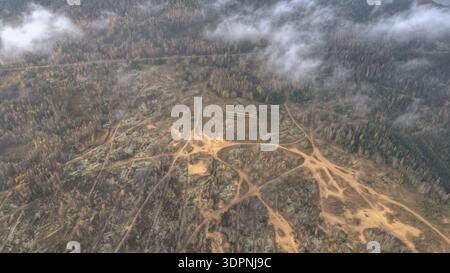 Aus der Vogelperspektive des Trainingsplatzes Dretunski in Belarus zeigt Sandwege, Mischwald und niedrige Wolken. Eine Betondecke sitzt auf einem Anstieg in sanfter Autu Stockfoto