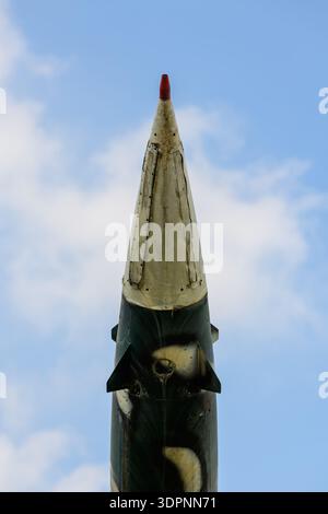 Hanoi, Vietnam - 9. Januar 2020: Aufwärtsansicht des Nasenabschnitts einer Rakete mit Tarnfarbe und roter Spitze, ausgestellt im B-52 Victory Museum vor blauem Himmel mit Wolken. Stockfoto