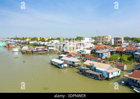 Chau Doc, Vietnam - 24. Januar 2020: Schwimmende Häuser und Boote befinden sich am Flussufer, hinter denen Stelzengebäude und Wohngebäude unter klarem blauen Himmel sichtbar sind. Stockfoto