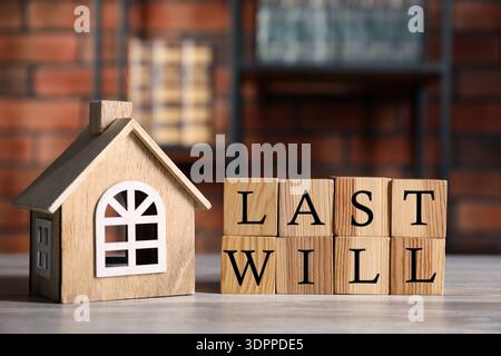 Letzter Wille. Worte aus Würfeln mit Buchstaben und Hausmodell auf Holztisch Stockfoto