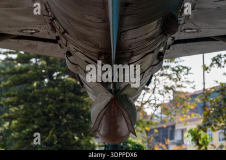 Hanoi, Vietnam - 9. Januar 2020: Nahaufnahme eines Düsenflugzeugs mit einer montierten Bombe oder Rakete im Freien im B-52 Victory Museum, mit Bäumen und Gebäuden im Hintergrund. Stockfoto