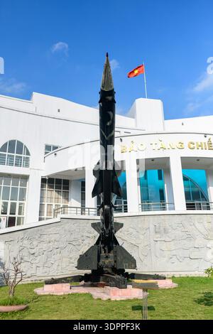 Hanoi, Vietnam - 9. Januar 2020: Eine Boden-Luft-Rakete wird auf einem Trägerraketen vor dem B-52 Victory Museum ausgestellt, wobei das Museumsgebäude und die vietnamesische Flagge im Hintergrund sichtbar sind. Stockfoto