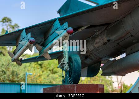 Hanoi, Vietnam - 9. Januar 2020: Nahaufnahme eines Düsenflugzeugs mit montierten Raketen und Fahrwerk, ausgestellt im Freien im B-52 Victory Museum, mit Bäumen und einem Zaun im Hintergrund. Stockfoto