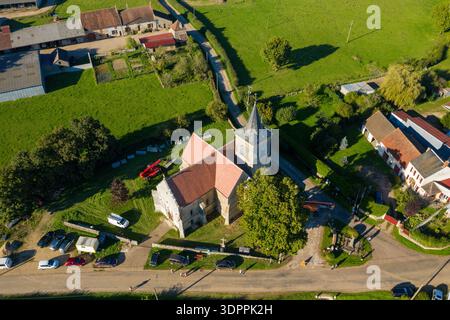 Cuncy, Frankreich - 30. September 2021: Aus der Vogelperspektive zeigt eine Steinkirche mit rotem Ziegeldach und Glockenturm, umgeben von geparkten Autos, Menschen, Baumaschinen und Dorfhäusern in einer ländlichen Landschaft. Stockfoto