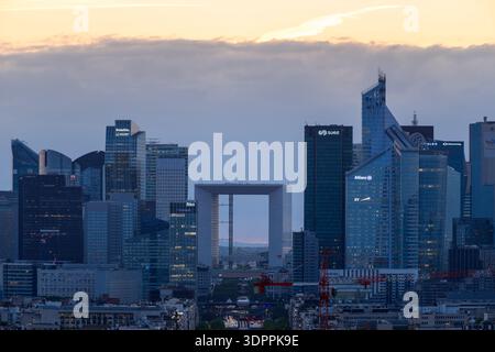 Paris, Frankreich - 11. Mai 2022: Blick auf die Skyline des Geschäftsviertels La Defense bei Sonnenuntergang mit dem Grande Arche und mehreren modernen Wolkenkratzern mit sichtbaren Firmenlogos wie Deloitte, Allianz, Suez und EY. Stockfoto