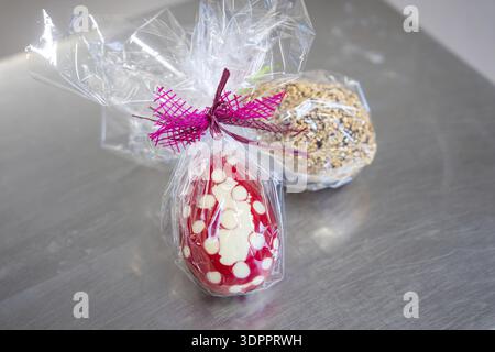 Zwei gewickelte Ostereier, eines rot-weiß mit Schleife, das andere mit Nüssen bedeckt, Osterproduktion regionaler Produkte, Haselstaller Hof, Stockfoto