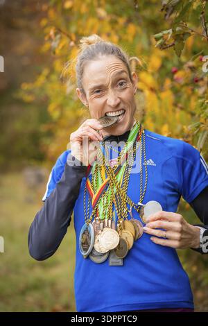 Frau mit Medaillen beißt spielerisch auf eine Medaille und lächelt, Mittelstreckenläuferin Katharina Jaiser, Gechingen, Deutschland Stockfoto