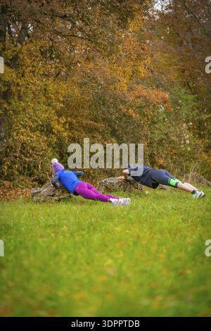 Zwei Leute, die Liegestütze auf Felsen in einem herbstlichen Wald machen, Mittelstreckenläuferin Katharina Jaiser, Gechingen, Deutschland Stockfoto