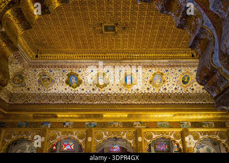 Jodhpur, Indien - 25. März 2022: Das Bild zeigt eine kunstvoll vergoldete Decke und einen verzierten Fries mit gemalten Porträtmedaillons, komplizierten Blumenmustern und Golddetails in einer Empfangshalle im Fort Mehrangarh. Stockfoto