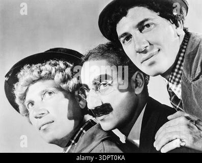 In dieser schwarz-weißen Publicity aus den 1930er Jahren sind drei der legendären Marx Brothers zu sehen: Harpo, Groucho und Chico Marx, von links nach rechts. Die legendären Comedians sind in ihrer Charakterform zu sehen, mit Groucho mit seinem charakteristischen fettfarbenen Schnurrbart und seiner Brille, Harpo mit seiner lockigen Perücke und dem Hut und Chico mit seiner unverwechselbaren Baskenmütze. Stockfoto