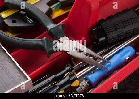 In einer Toolbox angeordnete Werkzeuge, die Zangen und verschiedene andere Instrumente für Reparaturarbeiten zeigen Stockfoto
