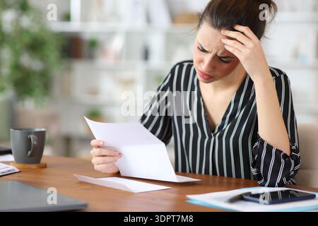 Besorgter freiberuflicher Mitarbeiter, der schlechte Nachrichten über Briefe liest, die zu Hause arbeiten Stockfoto