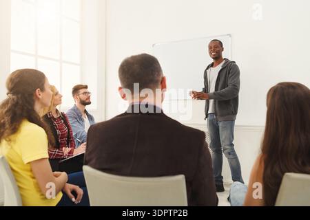 Die Gruppe lernt während der Workshop-Sitzung tagsüber vom Sprecher im modernen Raum Stockfoto