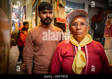 Eine ältere Frau und ein junger Mann, wahrscheinlich Touristen oder Pilger, posieren in einer überfüllten, engen Straße in Varanasi, Indien. Stockfoto