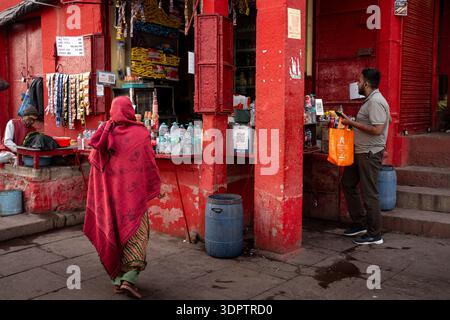 Eine offene Straßenszene fängt das tägliche Leben an einem pulsierenden roten Stand in der Nähe von Dashashwamedh Ghat in Varanasi, Indien, ein. Stockfoto
