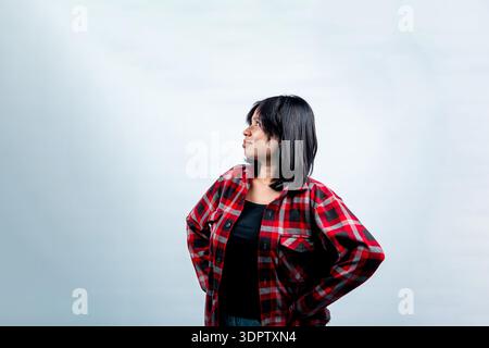 Selbstbewusste südostasiatische Frau in rotem Flanellhemd posiert in der Seitenansicht. Isoliertes Studio auf weißem Hintergrund, Vision und Jugend. Stockfoto