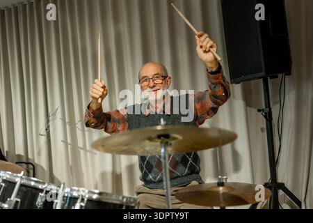 Ein älterer Mann genießt sein Hobby, das Trommeln spielt. Stockfoto