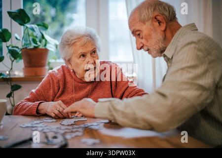 Seniorenpaar lösen gemeinsam Puzzle zu Hause. Stockfoto