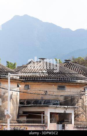 Traditionelles chinesisches Hofhaus mit Fliesendach, Bergkulisse, veraltete Architektur, ländliche Umgebung, verwitterte Wände, rustikaler Charme Stockfoto