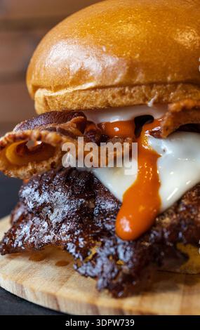 Gourmet-Burger mit knusprigem Speck, Käse und scharfer Sauce Stockfoto