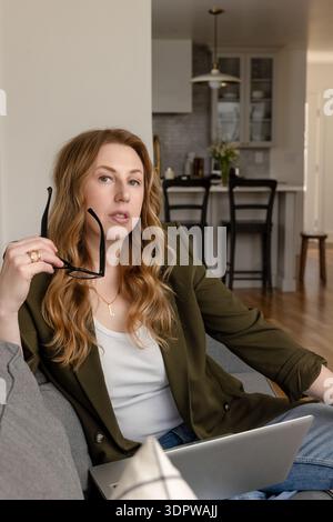 Selbstbewusste Frau im Alter von 40 Jahren, die zu Hause an einem Laptop arbeitet Stockfoto