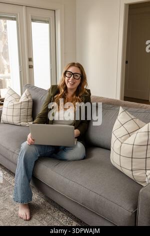 Lächelnde Frau, die im Wohnzimmer am Laptop arbeitet Stockfoto