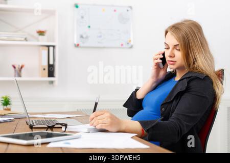 Frau, die tagsüber telefoniert, während sie am Schreibtisch in Büroumgebung arbeitet Stockfoto