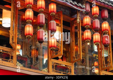 Traditionelle chinesische rote Lampions hängen an der Holzfassade in Chongqing, Sichuan, China. Festlicher Hintergrund und saisonale Feierlichkeiten Stockfoto