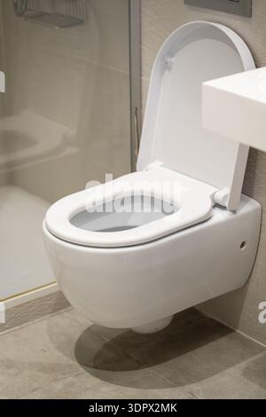 Weiße, an der Wand montierte Keramiktoilette mit offenem Deckel in einem modernen Badezimmer, die Sauberkeit, Hygiene und zeitgenössische Elemente der Inneneinrichtung betont Stockfoto