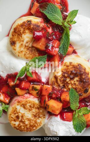 Syrniki-Pfannkuchen mit Beeren und Sauerrahm Stockfoto