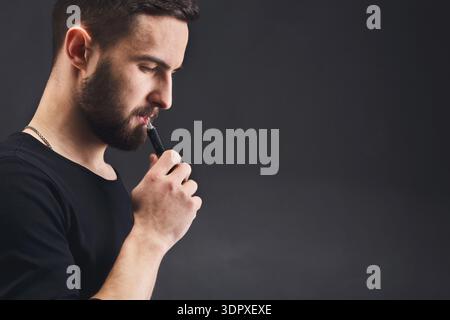 Rauchen vape. vaping Mann hält ein Mod. Vape Ringe. Ein Mann startet einen  Ring von Rauch. Tricks mit Rauch Stockfotografie