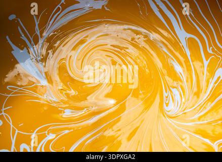 Abstrakte fließende Kunstmalerei in Acrylfarben, wirbelnde Farben, goldene gelbe und weiße Farben schaffen Stockfoto