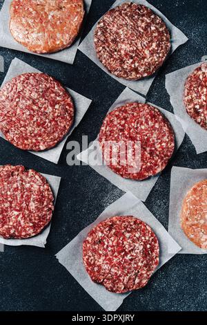 Ein Blick von oben auf frisches Kalb- und truthahnburger-Patties, die auf Pergamentpapier angeordnet sind, mit einer Vielzahl von Farben und Texturen, perfekt für einen köstlichen h Stockfoto
