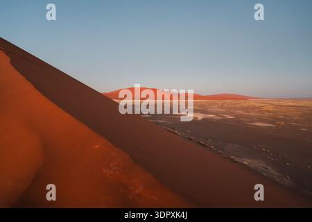 Atemberaubende Aussicht auf die Sossusvlei-Dünen in der Namib-Wüste, Namibia, mit sattem rotem Sand und weitläufigen Landschaften unter einem klaren blauen Himmel Stockfoto