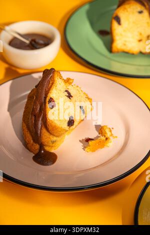 Ein köstliches Stück hausgemachter Biskuitkuchen mit geschmeidiger Schokoladensauce auf einem Teller. Dieses perfekt gebackene Dessert bietet klassische Bäckerei-Elega Stockfoto