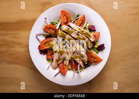 Ein köstlicher Teller Thunfischbauch-Salat mit frischen Kirschtomaten, knusprigen roten Zwiebeln und aromatischem Basilikum, alles in süßem Honig und Pistazien gekleidet Stockfoto