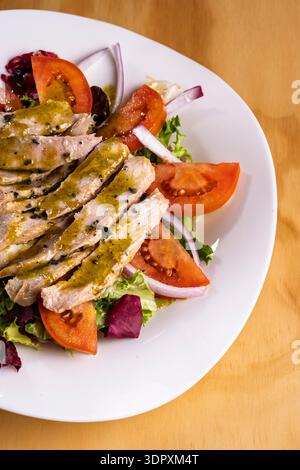 Ein köstlicher Teller Thunfischbauch-Salat mit frischen Kirschtomaten, knusprigen roten Zwiebeln und aromatischem Basilikum, alles in süßem Honig und Pistazien gekleidet Stockfoto