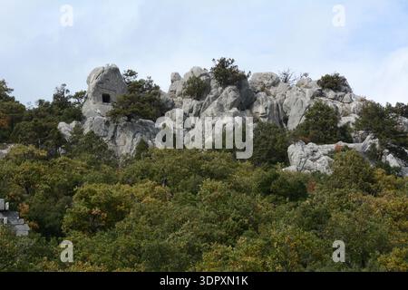 Ein felsiger, bewaldeter Hügel mit Felsgräbern in der antiken Stadt Termessos im Taurusgebirge bei Antalya, Türkei. Stockfoto