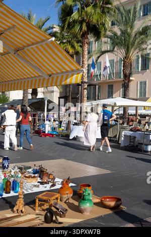 Flohmarkt im Freien in Nizza, Südfrankreich, mit Antiquitäten und Vintage-Objekten unter gestreiften Markisen und Palmen an einem sonnigen Tag. Stockfoto