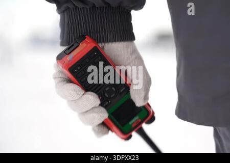 Ein Walkie-Talkie mit einer orangen Schutzhülle in der Hand eines Arbeiters in einem weißen Handschuh. Stockfoto