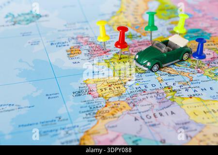 Kleines Spielzeugauto auf einer Karte mit bunten Stecknadeln an europäischen Standorten Stockfoto
